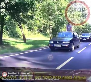 Mężczyzna trzymający się dachu jadącego samochodu na ulicy w Kwidzynie
