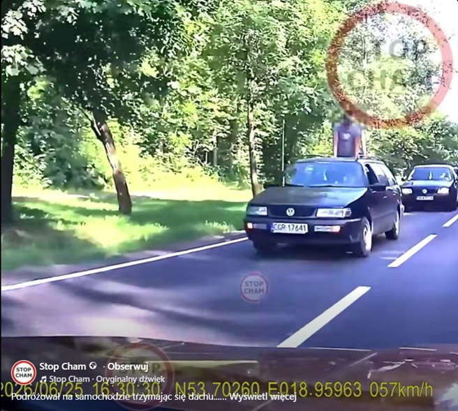 Mężczyzna trzymający się dachu jadącego samochodu na ulicy w Kwidzynie